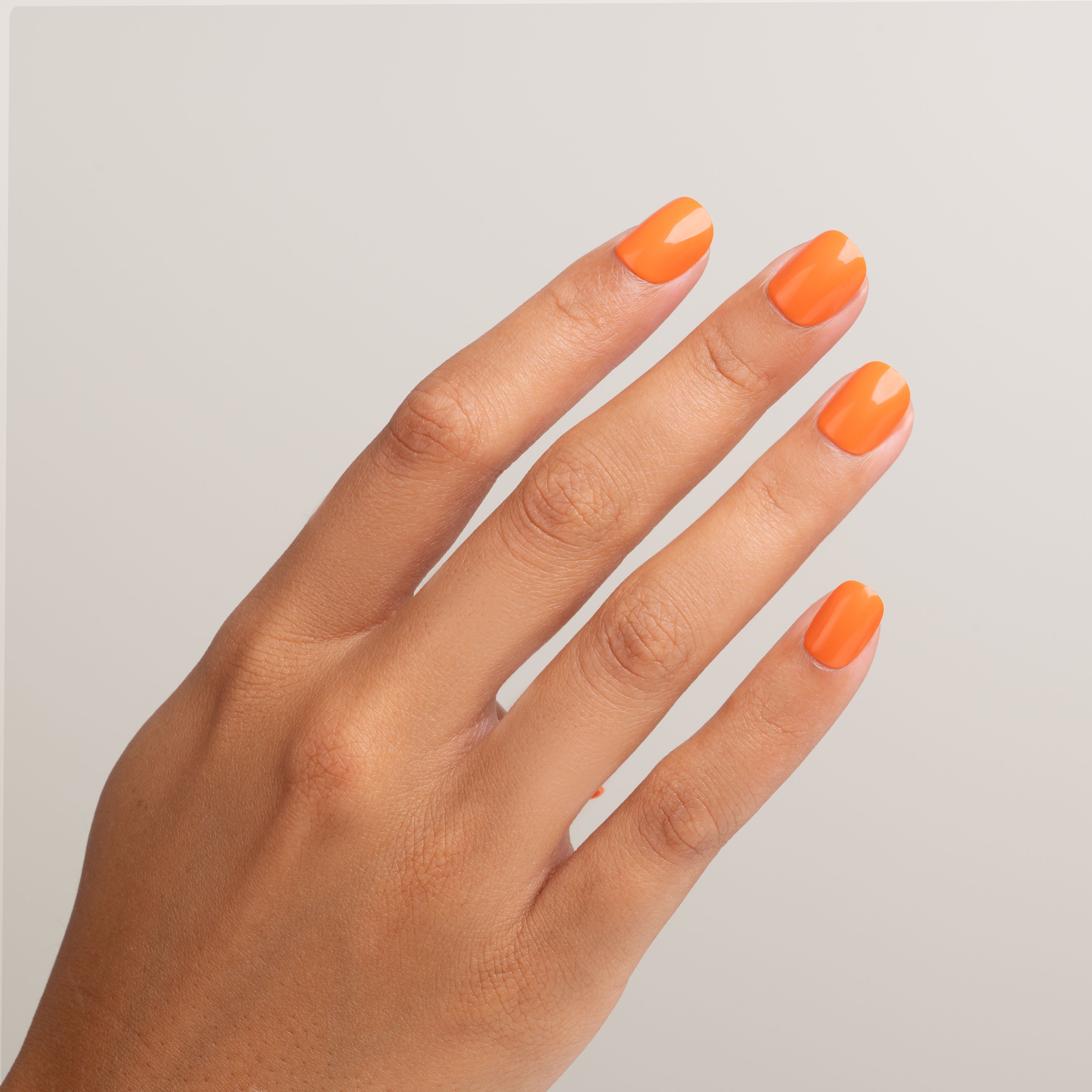 Hand with bright orange nail polish